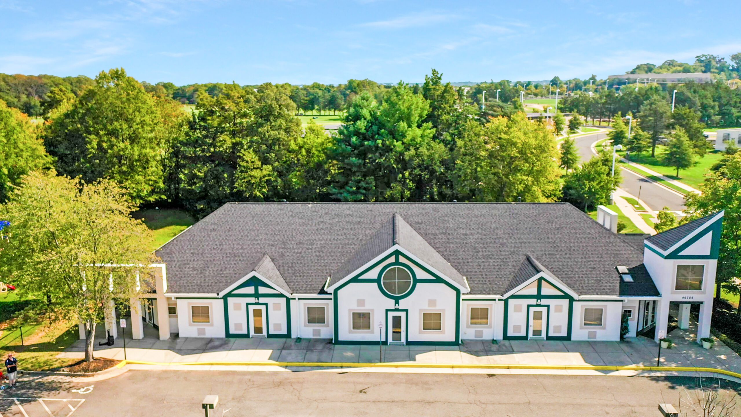 Aerial view of 46386 Logan Way, a childcare center in Sterling, VA, sold by Serafin Real Estate, featuring a unique architectural layout, playground areas, and ample parking.